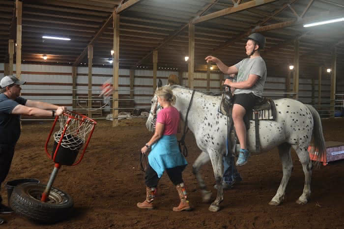 Jackson Shtein lights up as he throws a stuffed animal from the back of Jubilee at Harmony Ranch. The disability agency Chrysalis took summer campers to the ranch in Rathdrum for some equine therapy Thursday morning. Left to right: Sean Mahon, Peggy Zappone and Jackson Shtein.