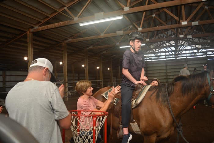 Hunter Nap receives a round of applause from Misha Shtein and Melissa Schroeder after succeeding during an equine therapy game at Harmony Ranch.