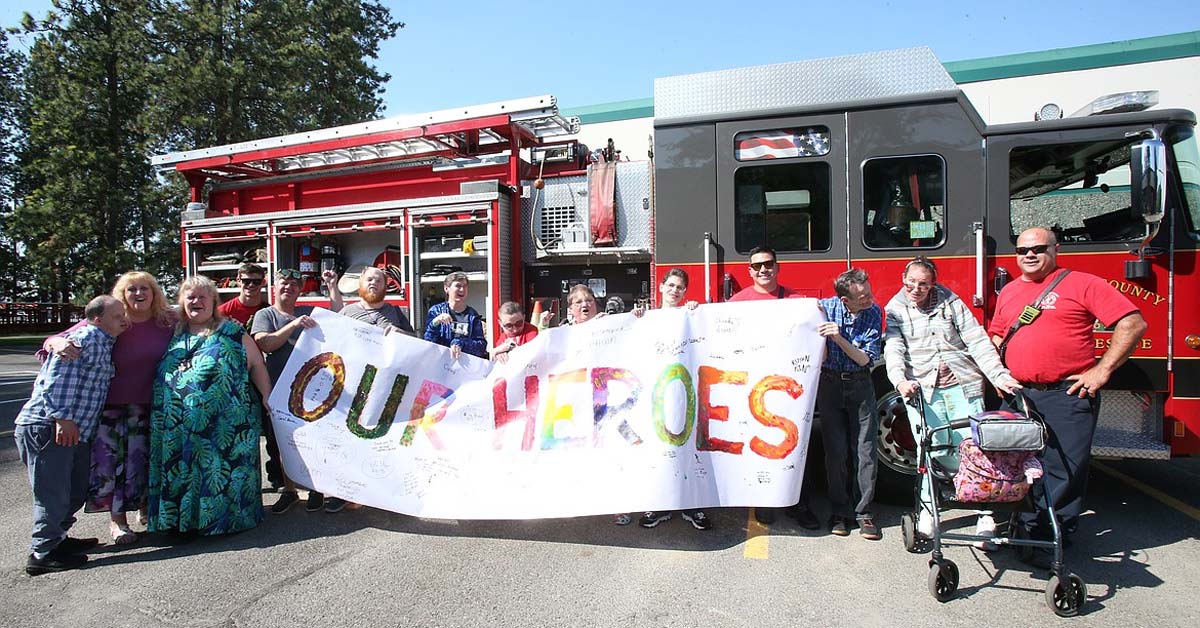 Chrysalis clients thank Kootenai County Fire and Rescue personnel Friday with a huge painted banner they've been working on all summer.